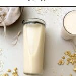 Cashews and coconut scattered around milk made in thermomix, in a jar laying on its side and a glass. Off to the top left is a bowl containing a nut milk bag and the pulp from making the milk