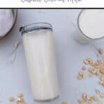 Cashews and coconut scattered around milk made in thermomix, in a jar laying on its side and a glass. Off to the top left is a bowl containing a nut milk bag and the pulp from making the milk