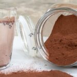 thermomix smilo milo chocolate powder in glass jar on its side on the right, left shows a glass of smilo with milk