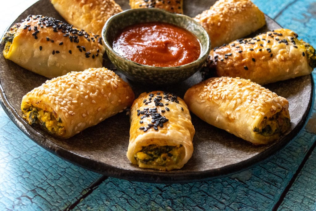 thermomix vegetarian rolls on plate in flower shape with bowl of tomato sauce in the middle, on crackly blue wood plank background