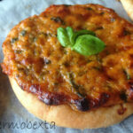 close up of pizza topped with tomato sauce, veggies and cheese, small piece of basil on top in the middle