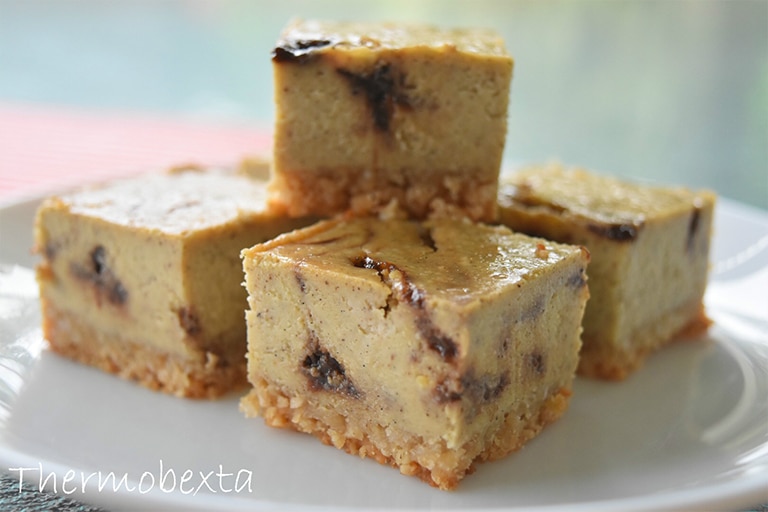 strawberry swirl baked cheesecake made in thermomix, cut into squares and sitting on white plate. Blurred background