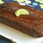 sticky lime and coconut loaf cake on white plate on floral tablecloth