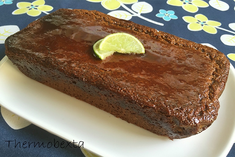 sticky lime and coconut loaf cake on white plate on floral tablecloth