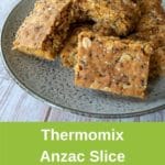 thermomix anzac slice on grey plate on white wood pinterest image