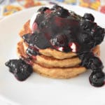 thermomix blueberry sauce drizzled over pancake stack on white plate