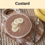 white bowl on wooden rustic board, brown choc banana custard in bowl with four slices of banana on top, bananas off to the side right hand top, cream banner above with recipe title