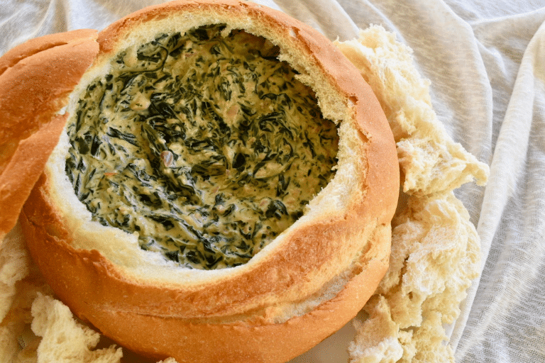 thermomix spinach cob loaf dip in cob loaf. Cream background with chunks of crusty bread around