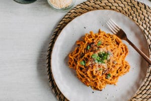 Spaghetti alla Puttanesca flexible thermomix meals, on a plate on woven placemat and light coloured table