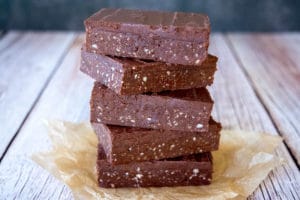 five slices healthy chocolate slice on top of each other, on top of two pieces of baking paper, on wooden table, black background