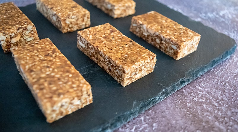 sesame bites portioned, sitting on black slate tile, on rustic dark tabletop