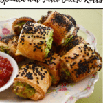 spinach and cheese rolls with black sesame seeds, on antique plate, with ramekin of sweet chilli jam, on green background