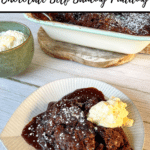 plate of chocolate self saucing pudding and cream in foreground, part of dish of cream and dish of pudding in background. All on grey and white backdrop with text above and below