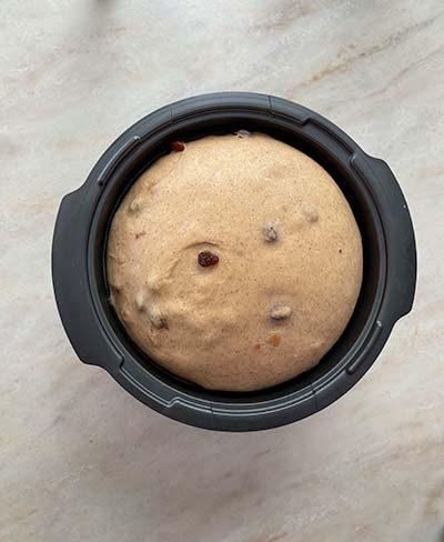 hot cross buns dough in black bowl on stone bench top, after rising