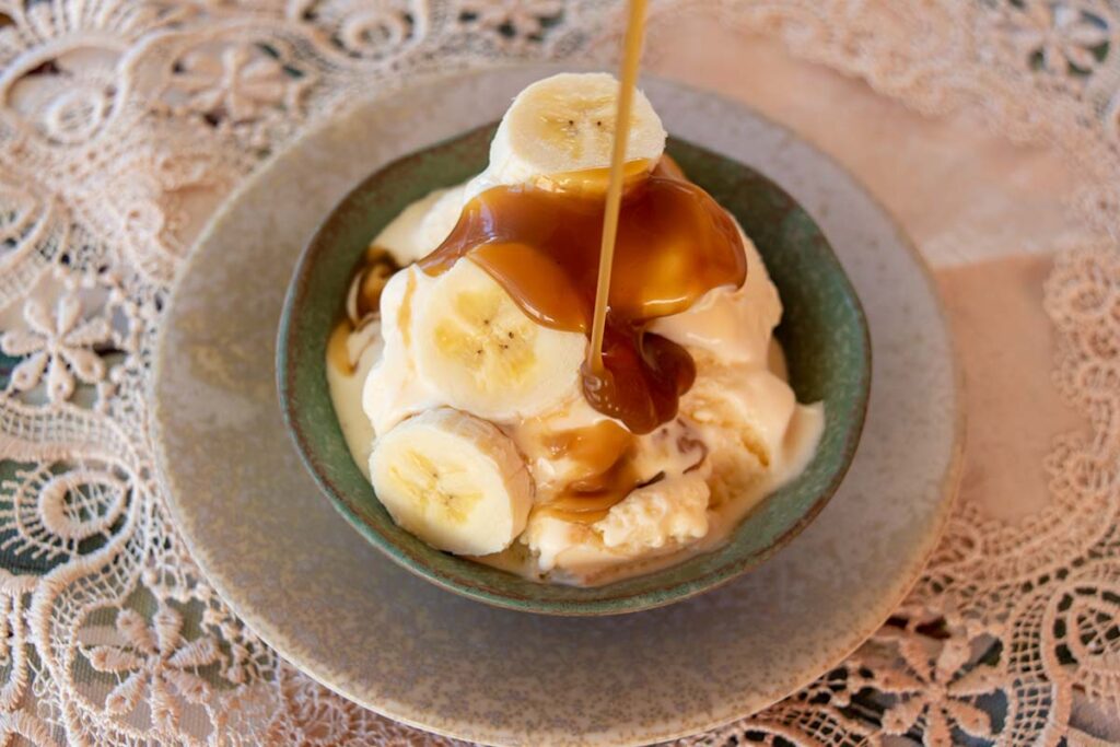 salted caramel maple sauce made in thermomix being drizzled onto a bowl of ice cream and bananas