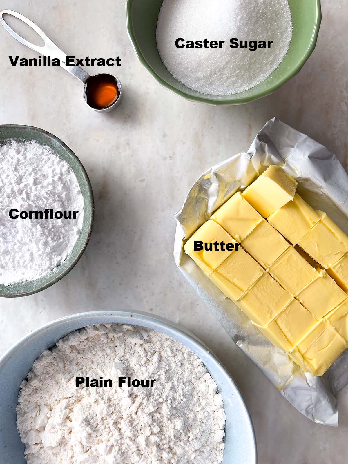 ingredients laid out for shortbread - caster sugar, butter, plain flour, cornflour, vanilla. All labelled.