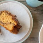 Slice of thermomix cinnamon crumble cake on white plate with fancy cake fork